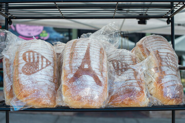 Loaves of thick white bread wrapped in clear plastic bags on a wire rack.There are scoured shapes...