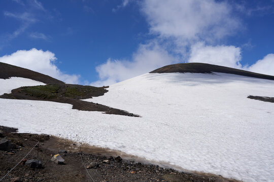 Climbers are slowly descending the large snow valley that spreads out on the eastern slope of Mt. Asahidake.