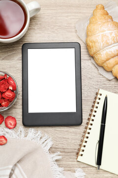 E-book reader with breakfast and notebook on wooden table, flat lay. Space for text