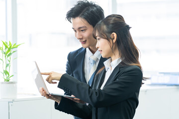 笑顔でパソコンを見て話す日本人男女