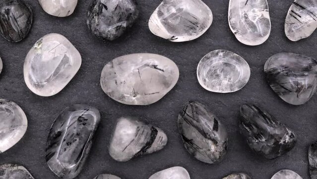 Tourmalinated quartz rare jewel stones texture on black stone background. Moving right seamless loop backdrop.