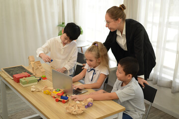 Teacher teaching her young students drawing toys or wood model on the laptop.