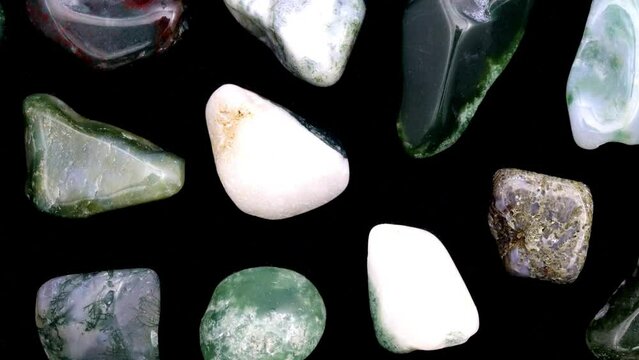 Moss agate rare jewel stones texture on black background. Moving right seamless loop backdrop.
