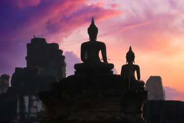 Silhouette look of Ancient Buddha statues facing a colorful morning cloud and sky at Wat Pra Pai...