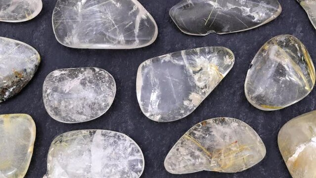 Rutilated quartz rare jewel stones texture on black stone background. Moving right seamless loop backdrop.