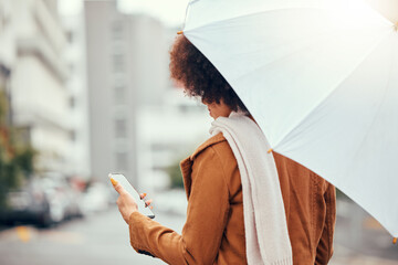 Umbrella, phone and woman in a street during rain, winter and morning in the city while texting,...