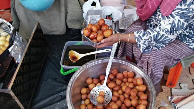 Arabic woman preparing Arabic traditional dessert luqaimat. Traditional Emirati sweet serve with sesame seeds and date syrup.