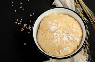 Raw dough pastry in a bowl on dark background.