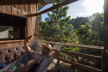 tourist taking a selfie in a background hammock in a cabin on a sunny morning in the tropical jungle