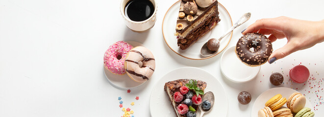 Table with various cookies, donuts, cakes,  coffee cups on white  background.