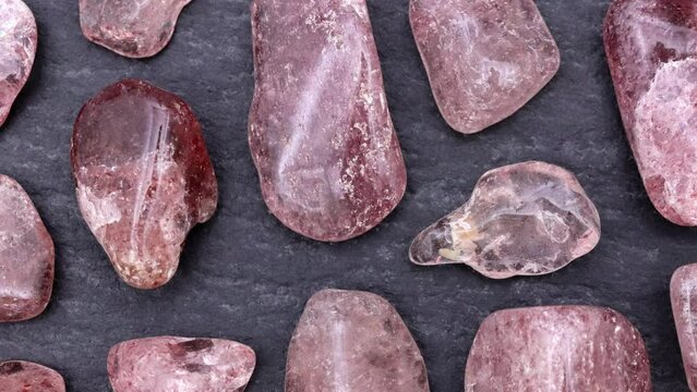 Strawberry quartz rare jewel stones texture on black stone background. Moving right seamless loop backdrop.