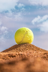 Tennis ball on the floor on a clay court against the sky