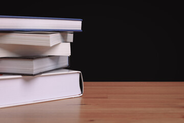 A pile of stacking old book in bookshelf put on wooden table with black background. Education textbook, study and library concept.