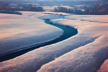 Aerial rural landscape in winter. View from above of narrow brook and countryside in snowy winter. Nature landscape