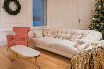 New year, christmas ,scandinavian scandi interior. armchair ,beige sofa and christmas tree decorated in golden colors. New year decoration idea. Stylish interior of living room
