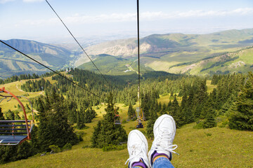 Summer mountain landscape high in the mountains. Tall trees of Christmas trees, ski lift at the ski...
