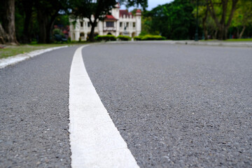 Fototapeta premium White Line on the Asphalt Road in the Park. (Selective Focus)