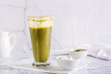 Green matcha cheese tea in a glass on the table. Homemade trendy drink.