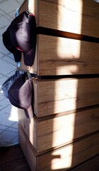 A home chest of drawers with baseball caps hanging on it, with the glare of the sun.