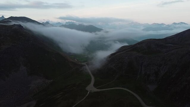 Cars leaving Hatcher Pass Clouds Rolling through Valley Alaskan Mountain Range druing the Day