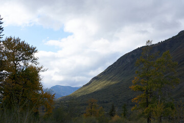 Mountains in the evening in the fall, against the background of the sky with clouds. Beautiful photo wallpaper.