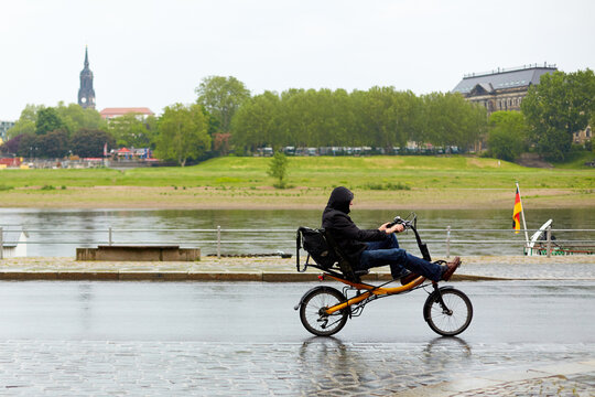 A guy is riding around a city in Europe on a bicycle with an unusual, almost reclining posture