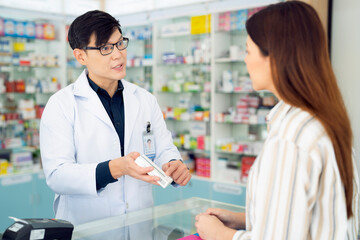 Asian pharmacist man explain how to use a drug and medicine to his customer