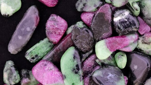 Ruby zoisite jewel stones heap up texture on black background. Moving right seamless loop backdrop.
