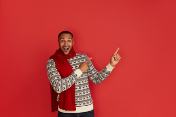 Shocked Man Pointing Aside. Astonished Multiracial Guy in Pointing at Copy Space and Looking With Amazement. Indoor Studio Shot Isolated on Red Background 