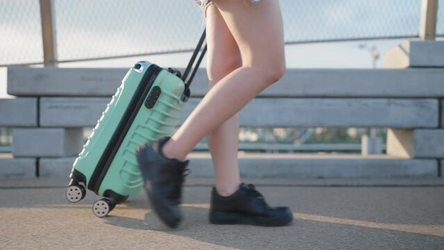 Close up legs of woman tourists dragging suitcases