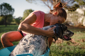 Redheaded woman hugging her dog while giving him a bath. Pet care concept.