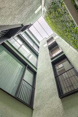 Lookup view of modern residential building. Black frame windows and vertical gardening in Barcelona.