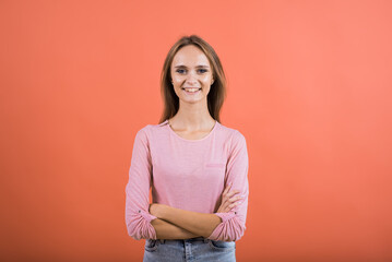 Fototapeta premium Portrait of a happy girl with crossed arms who smiles on a red background.