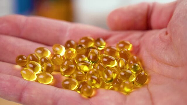 Omega 3 translucent golden capsules. Handful of dietary nutritional supplements in hand. Close-up. Polyunsaturated fatty acids