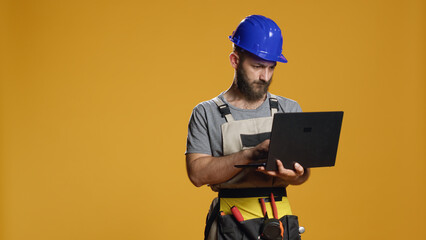 Portrait of handyman using laptop to find construction inspiration and work on refurbishment scheme...