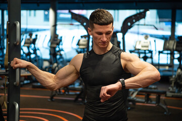 sportsman checking up fitness tracker in gym. Athletic sportsman monitoring fitness training in gym.