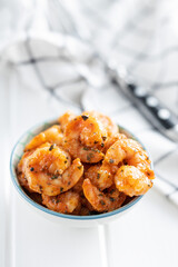 Grilled tiger shrimps in bowl on white table.