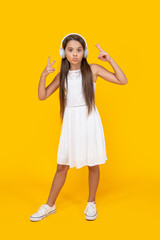 teen girl listen music in headphones on yellow background. peace