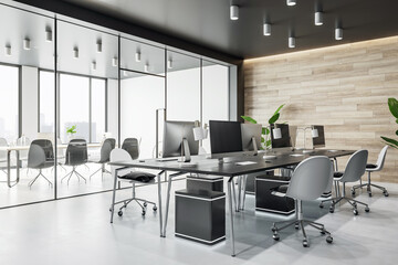 Perspective view on stylish workspace with modern computers in spacious coworking office with glass partitions, wooden wall and light grey floor. 3D rendering