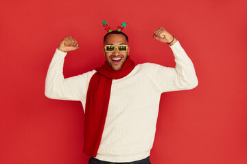 Winner Man Rejoicing Studio. Extremely Happy Multiracial Guy Raised Arm Gesturing Yes I Did It, I'm Winner, Feeling Energetic and Lively. Isolated on Red Background 