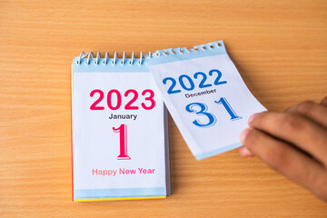 Close up shot of hands changing calendar to New Year 2023 by removing 2022 - concept of new...