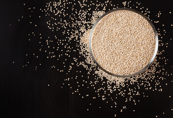 Dried white quinoa seeds on black wooden background