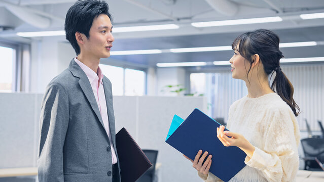 オフィスで会話する若い会社員男女