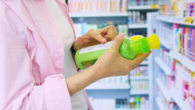 Close-up in the hands of a woman bottles with shampoo for hair restoration. Selection in the store of shampoo for hair. Buying hair care products. Woman shopping for shampoo and hair balm