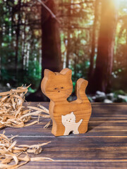 Wooden puzzle in the form of a handmade cat family on the background of the forest
