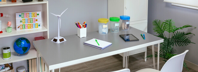 Empty environmental classroom with selective trash bins and windmill over table. Ecologic education concept.
