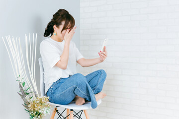 スマホで通話しながらショックを受けるアジア人女性（泣く・悲しい）
