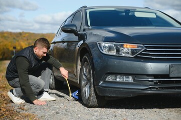 Man with broken down car flat tire in the middle of the street