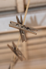 A line of old wooden clothes pegs on a nylon washing line with rusty metal springs make an attractive arrangement against a dark and creamy background