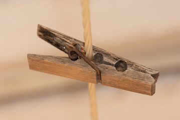 A line of old wooden clothes pegs on a nylon washing line with rusty metal springs make an attractive arrangement against a dark and creamy background